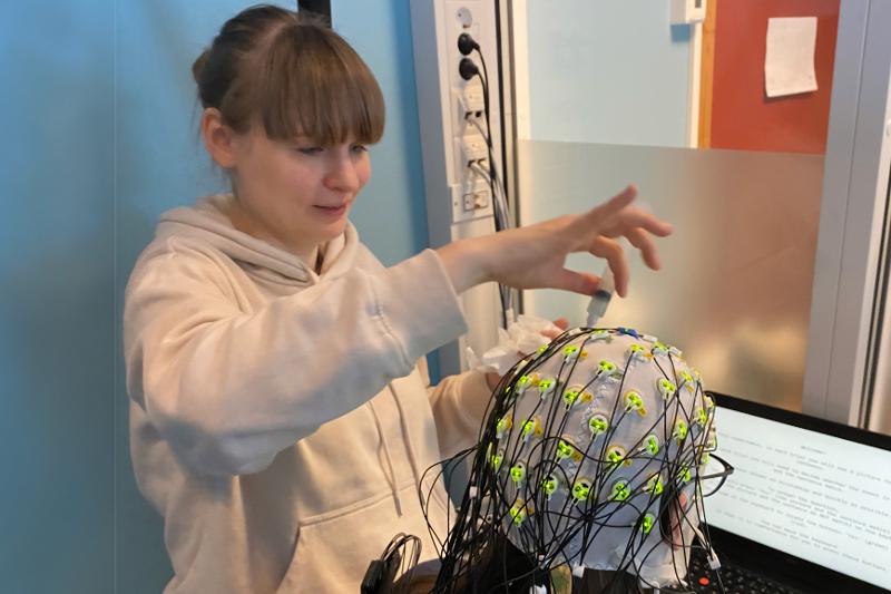 Ei kvinne festar EEG-målarar på ein person.